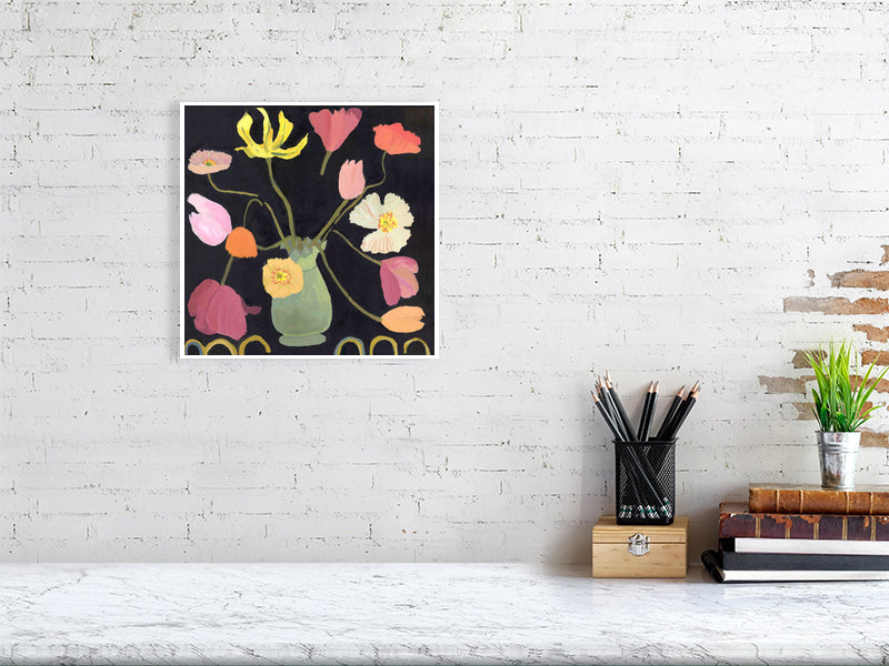 Square Giclée flower print of tulips and poppies in a green vase, mounted on a white brick wall above a desk with stationery.