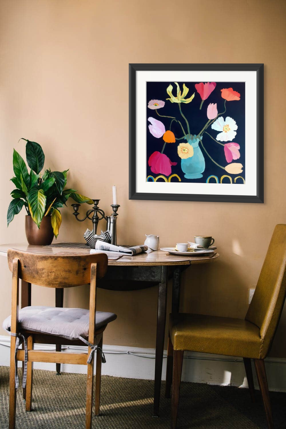 Framed Giclée flower print of tulips and poppies in a cozy dining room setting with warm tones and a green potted plant.