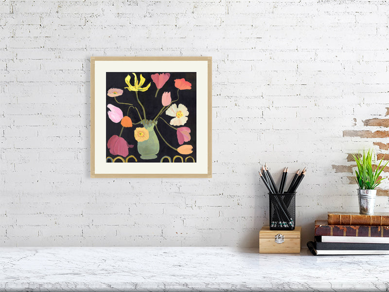Framed Giclée flower print of tulips and poppies in a green vase, elegantly displayed on a white brick wall with minimal decor.
