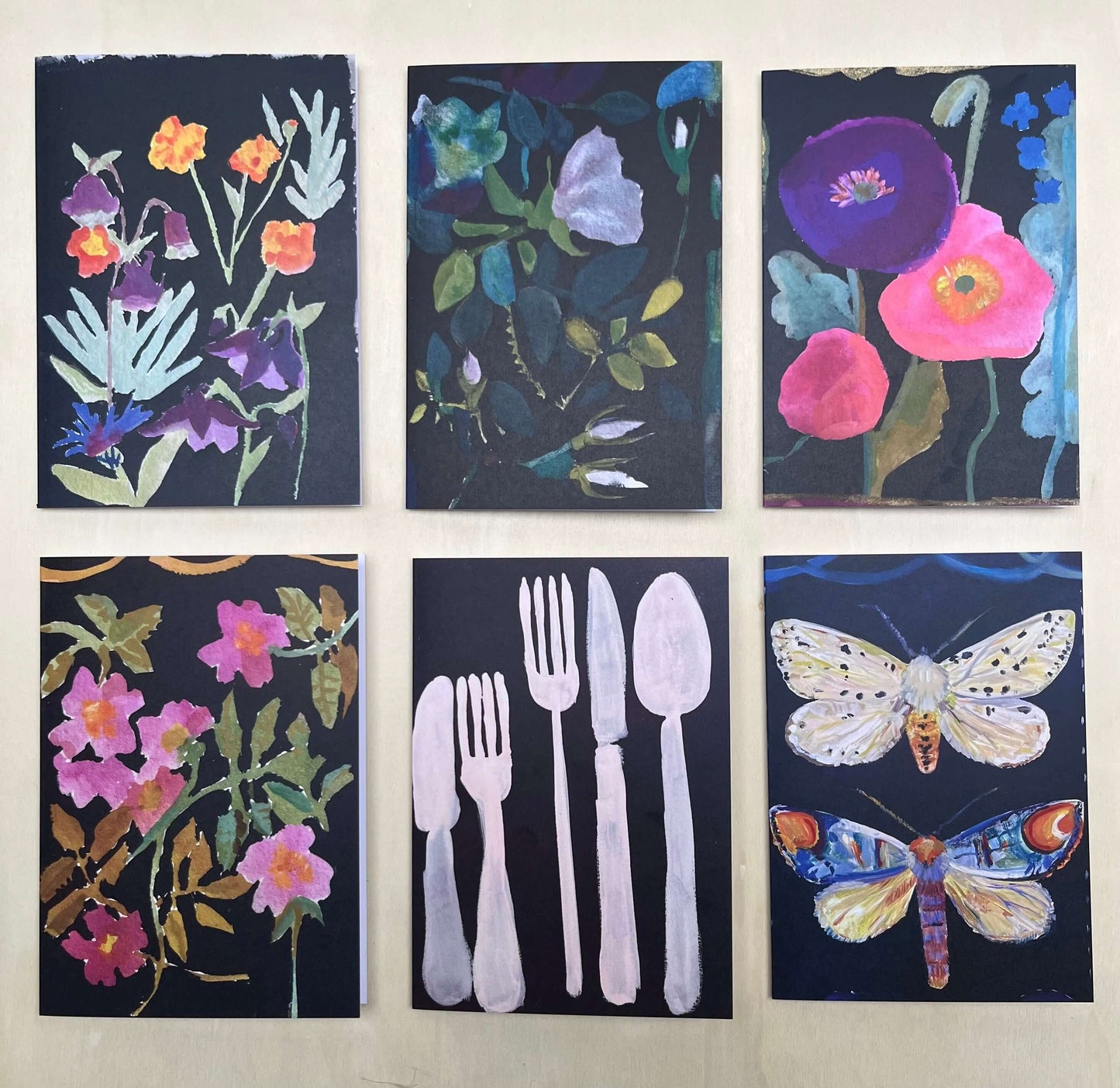 Box of 6 fine art greetings cards featuring floral and nature designs in vibrant colors on a dark background.